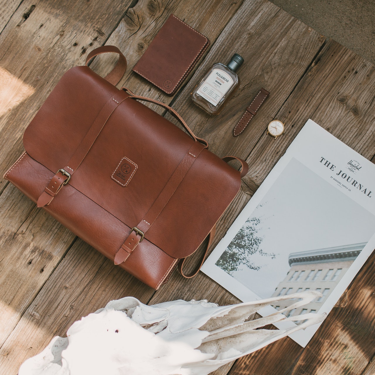 A leather bag, wallet, and magazine on a wooden table